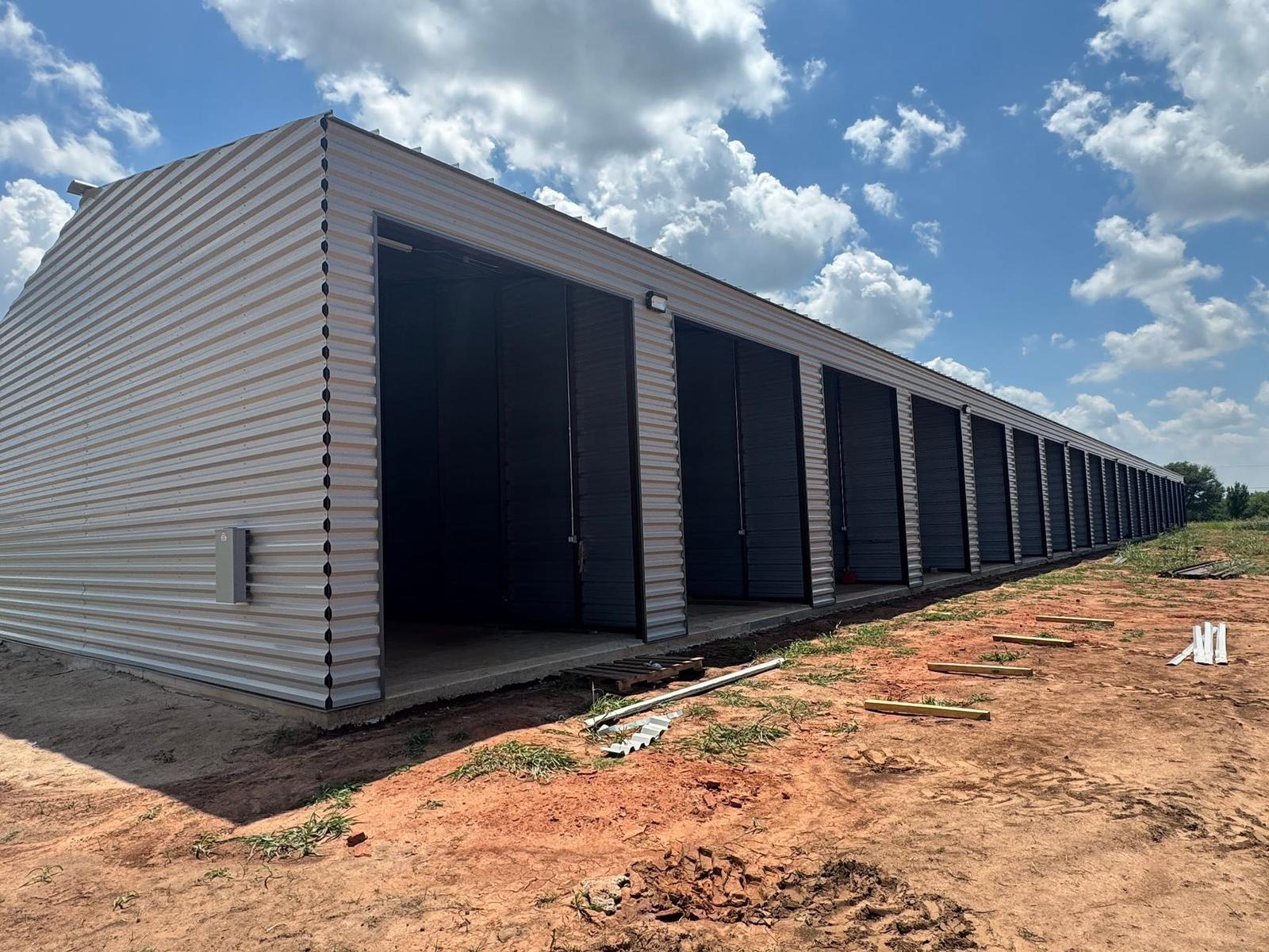 The first enclosed storage building standing on the red dirt of the property
